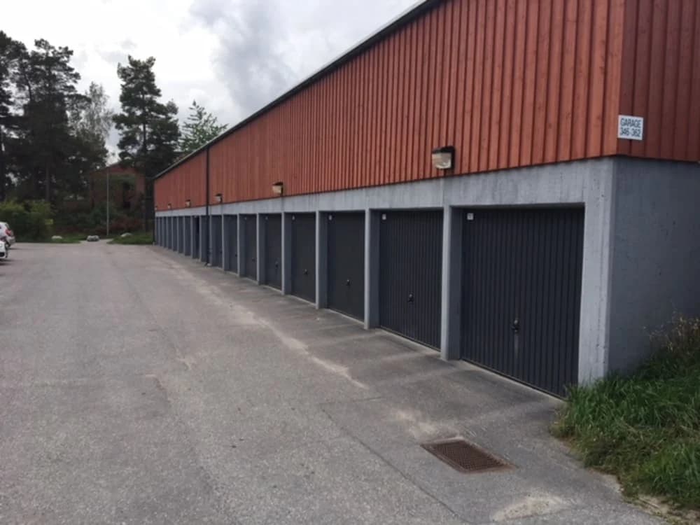 Rondovägen med parkerade bilar och flera garage i rad.