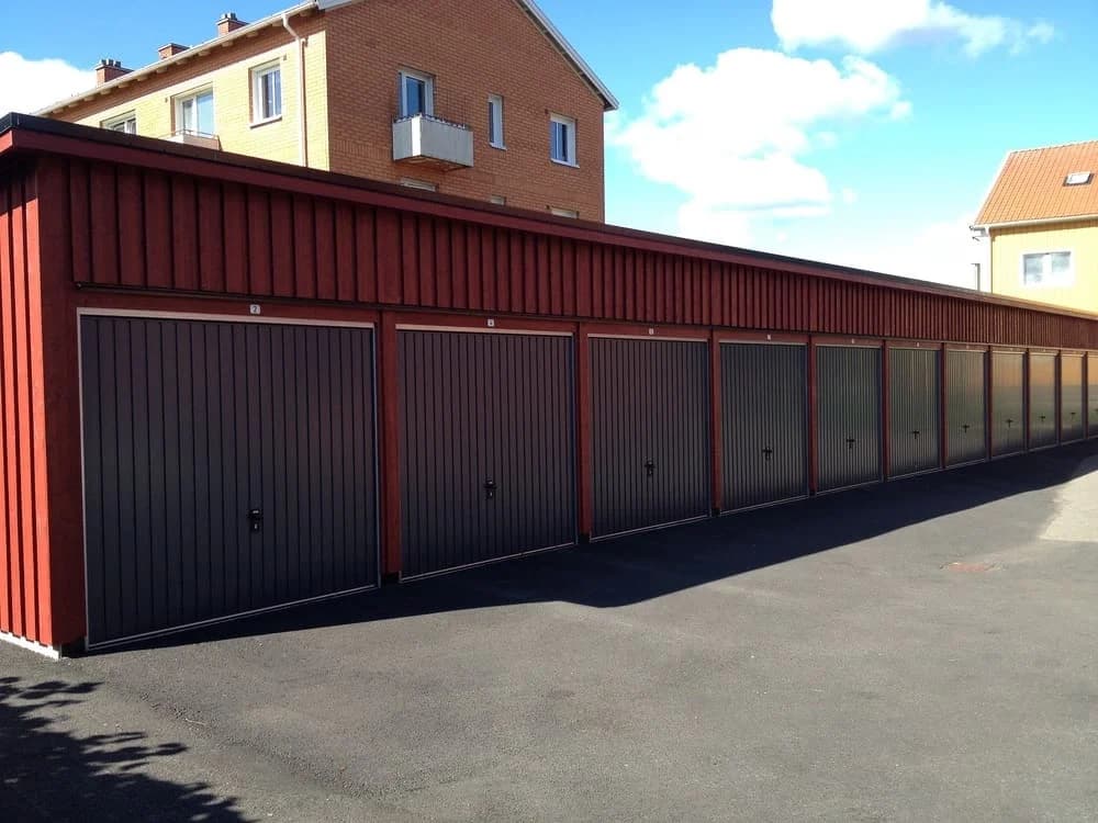 Garage i röd träpanel med flera dörrar på Älgstigen.