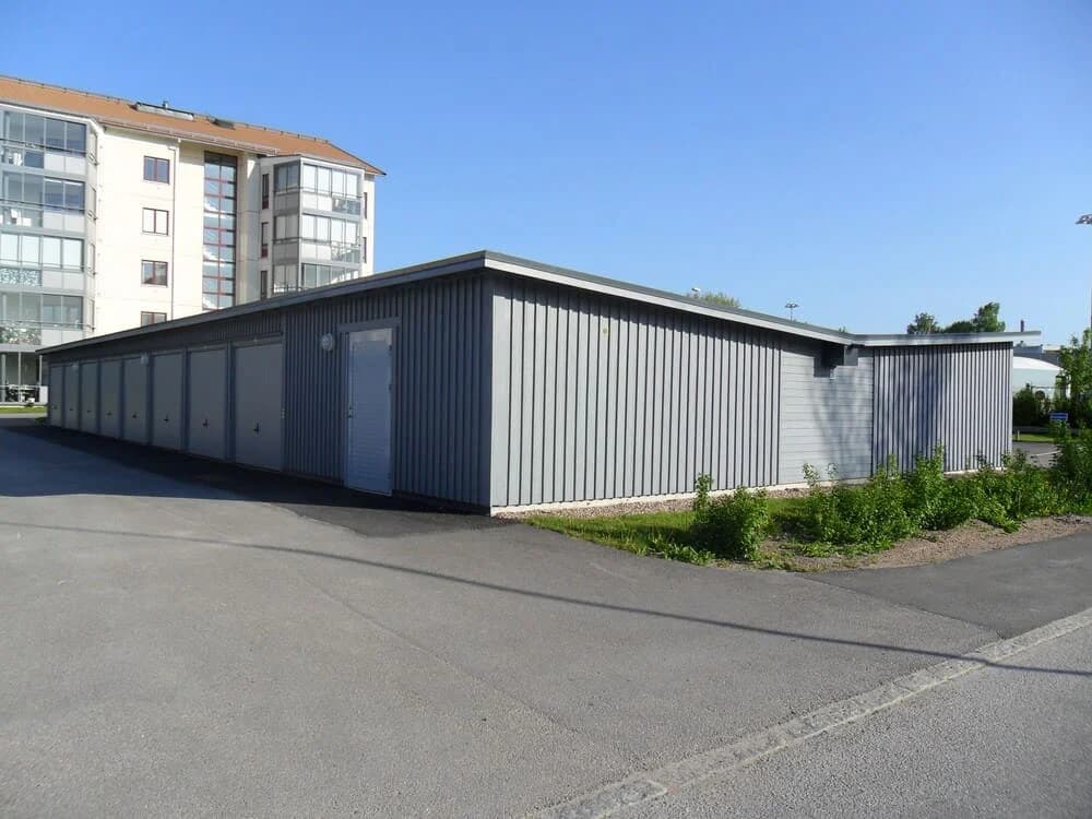 Guldsmeden: Gråbyggnad med flera garage i soligt område.
