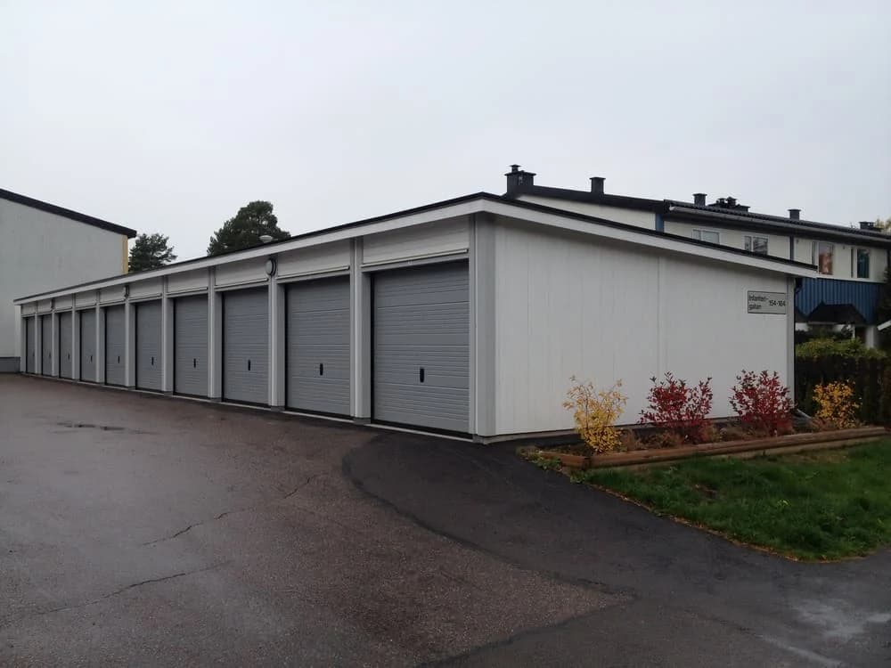 Flera garage med grå dörrar längs en asfalterad väg.