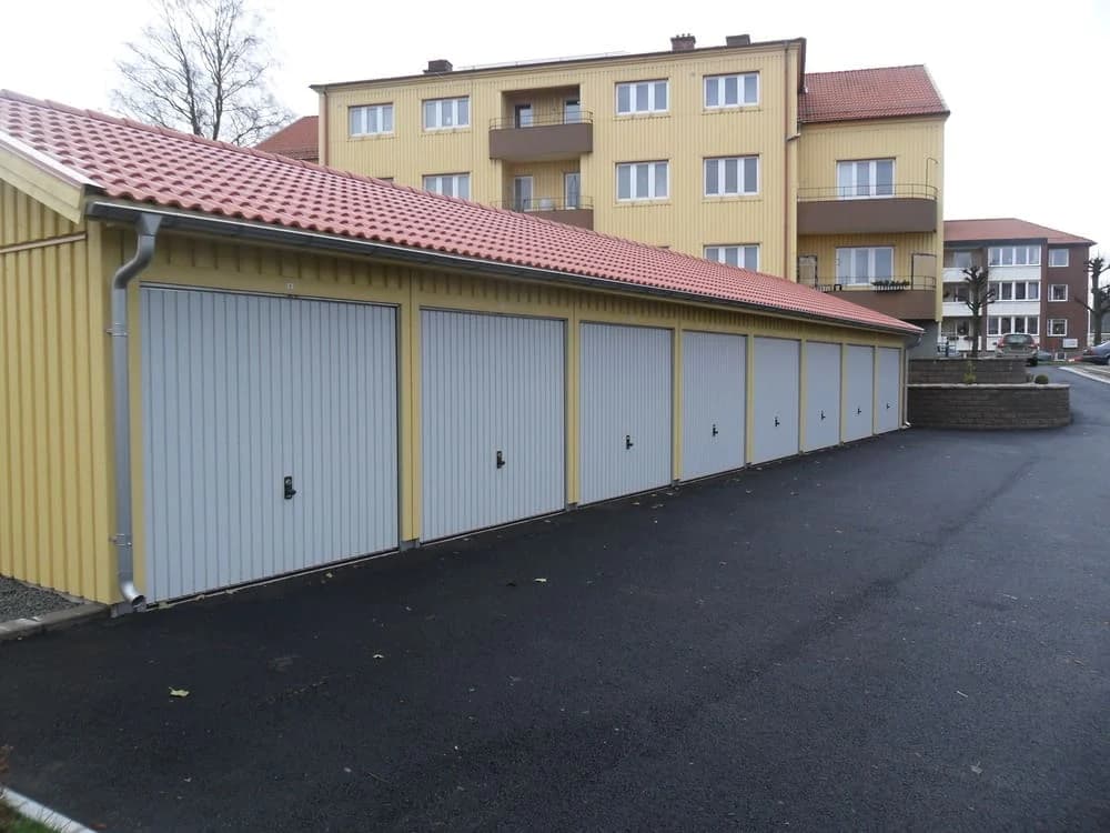 Flera garageportar vid en gul tvåvåningsbyggnad.