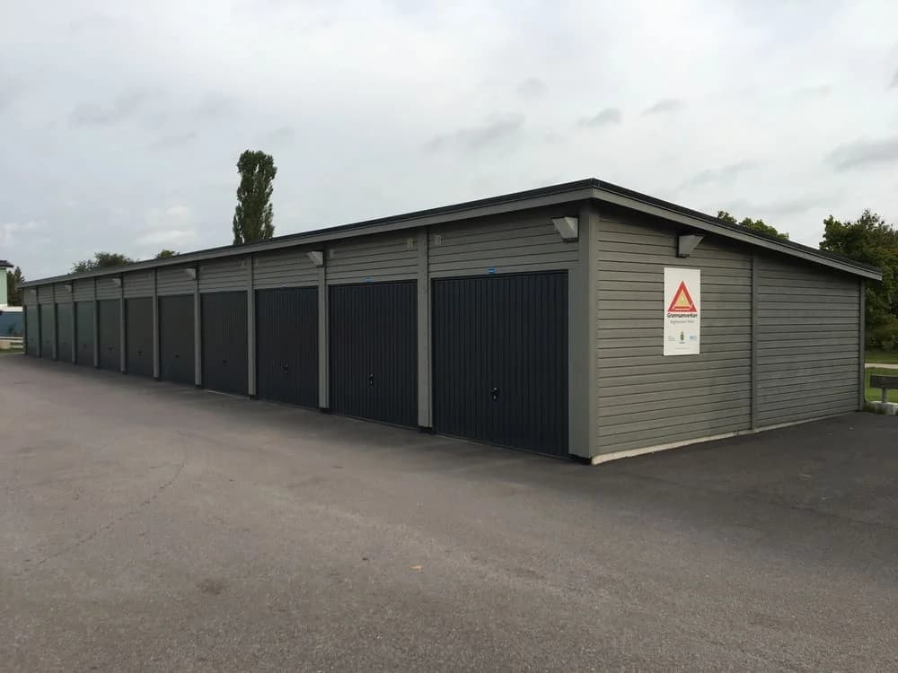 Skälby: Byggnad med flera garageportar längs en asfaltväg.
