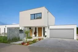 Modern villa med sektionerade portar och grönskande landskap.