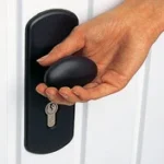 Hand som håller i en rund svart nyckelknopp vid dörrlås.