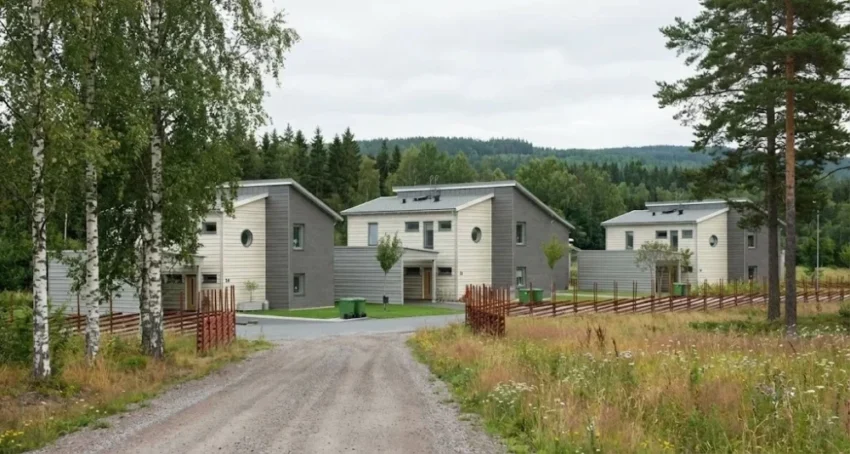 Tre moderna hus omgivna av natur och grönska.